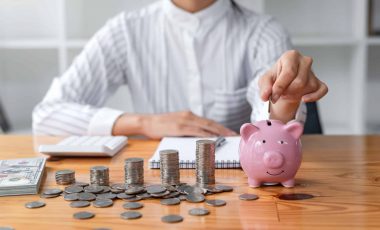 Businesswoman hand putting coin to pink piggy bank saving. Concept business, finance, money saving and investment.