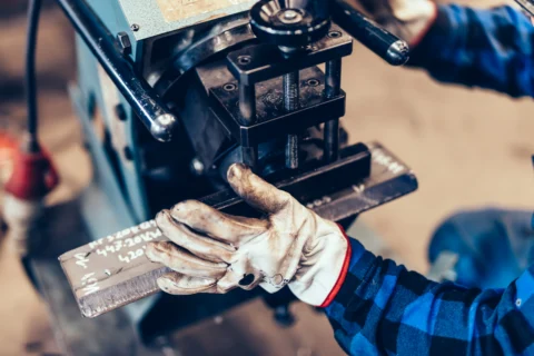 Operator at a high-volume stamping press during a manufacturing process improvement project.