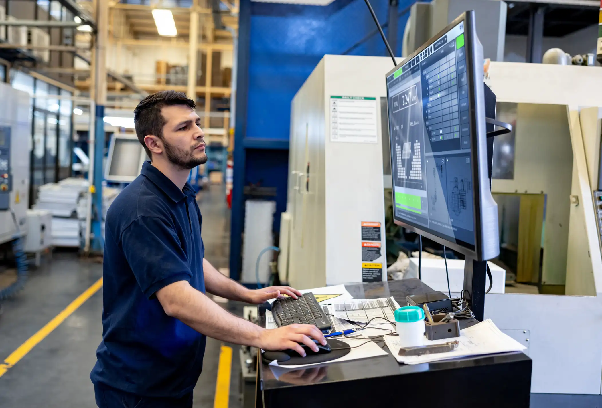 manufacturing worker using visual management system at computer as part of 5S Standardize process improvements