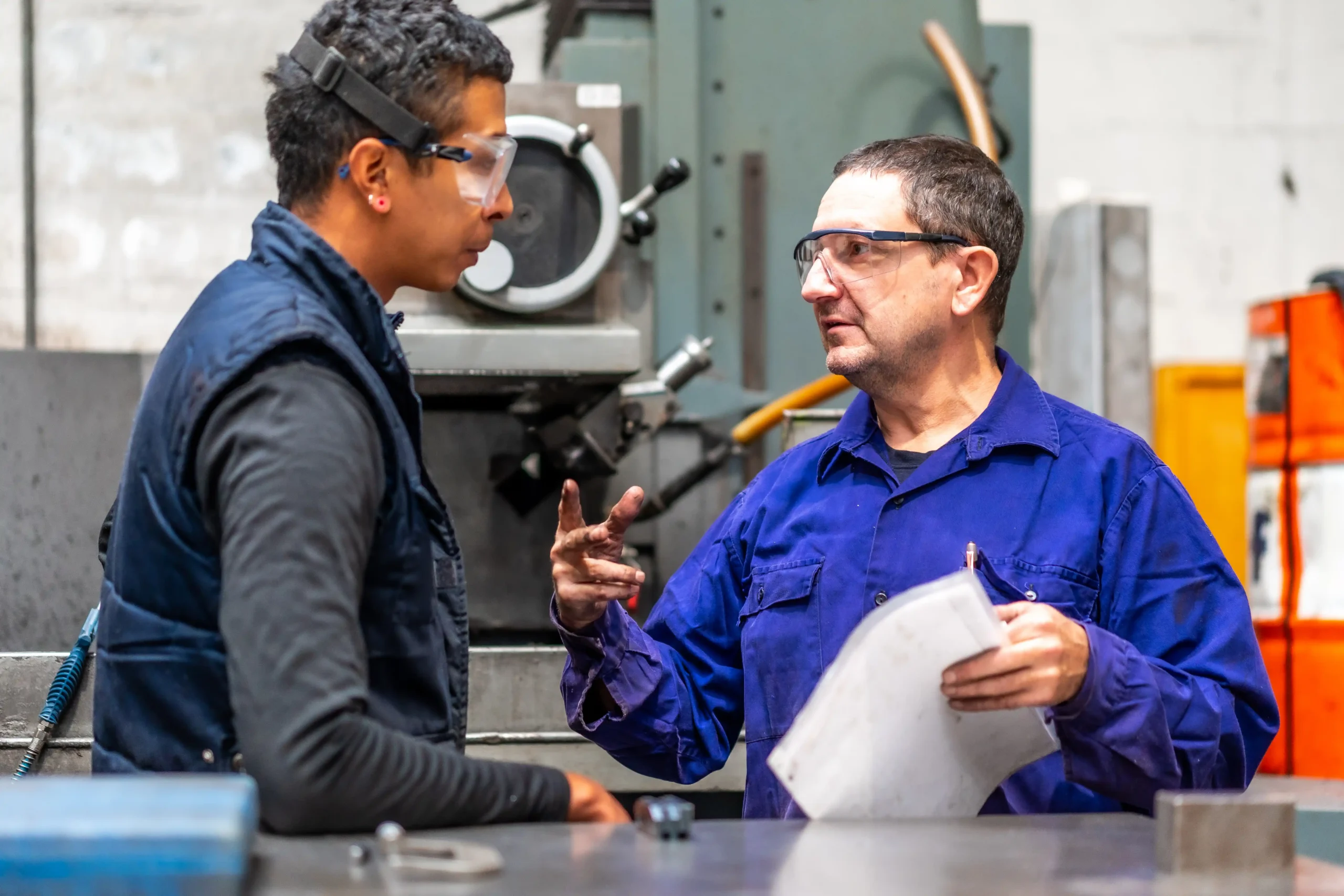 Plant manager reviewing flow and constraints with a supervisor on a manufacturing floor shows operational excellence leadership behavior in practice