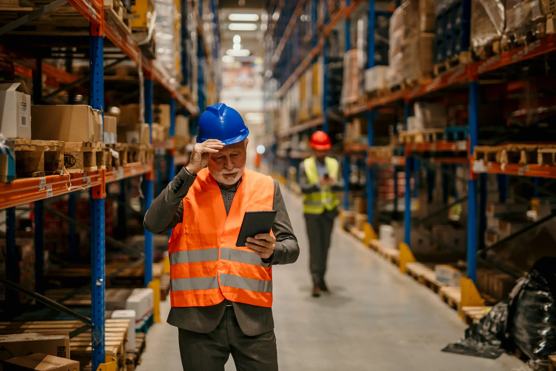 tired man looking at tablet in warehouse run with lean systems